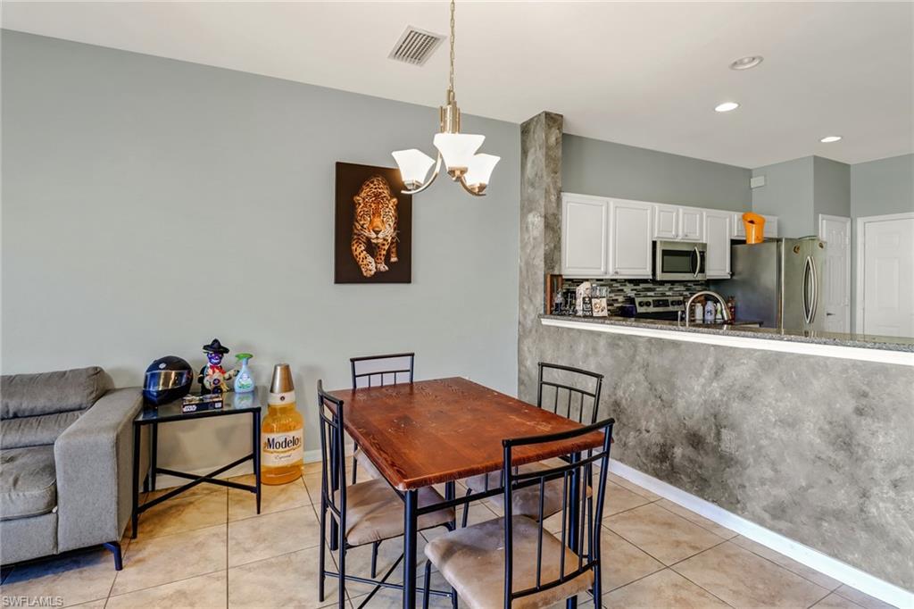 977 Hampton Circle, Unit 118 Naples, FL 34105 - Photo 8 of 24 a kitchen that has a table chairs and a refrigerator