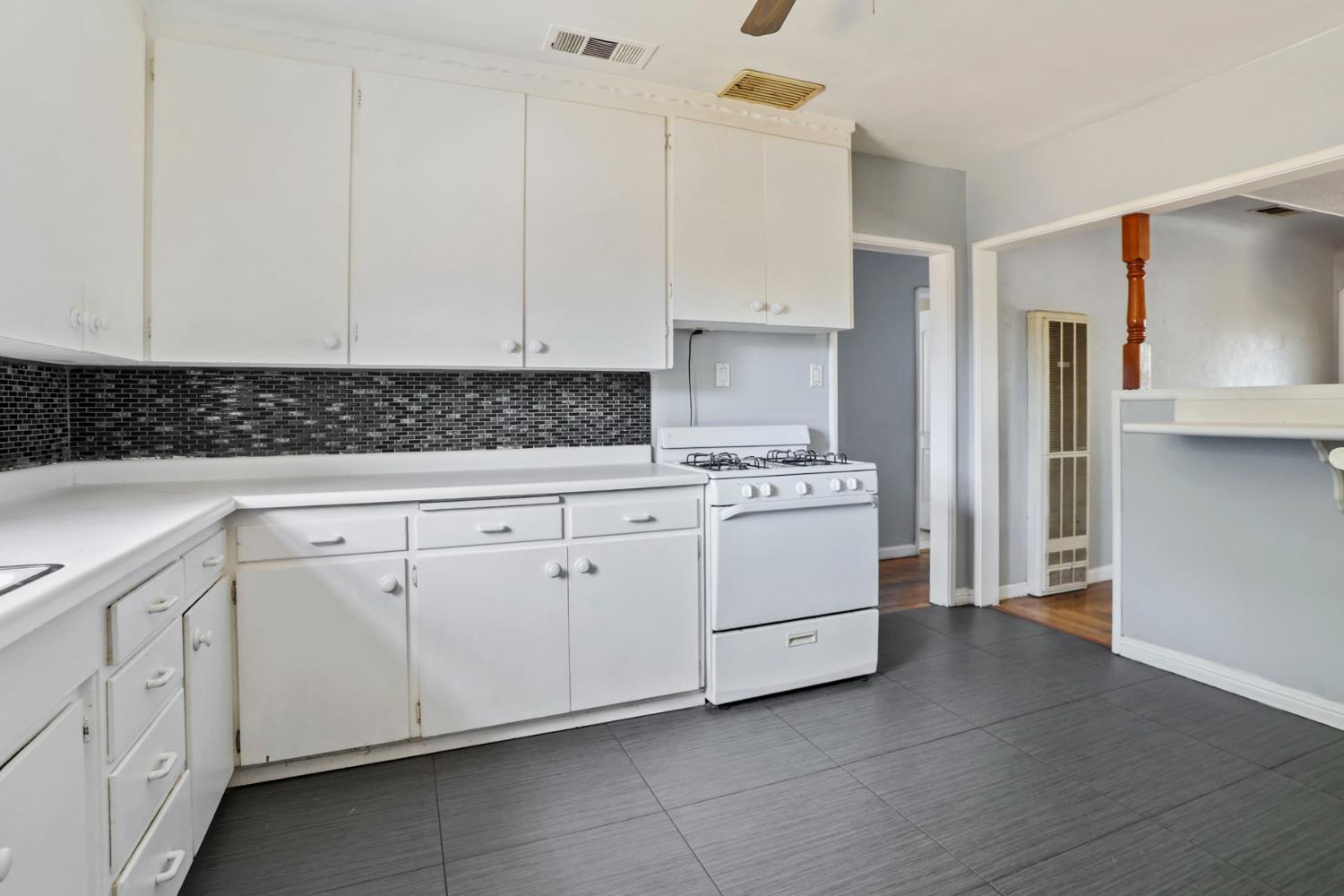 916 Elm Avenue Modesto, CA 95351 - Photo 14 of 52 15. Kitchen with stove view A clean, practical kitchen layout with updated tile flooring, classic cabinets, and a backsplash that adds a little modern contrast.