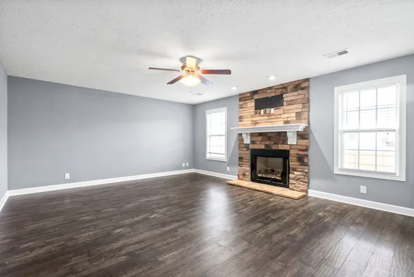 an empty room with windows fireplace and wooden floor