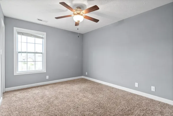 an empty room with a window and a fan