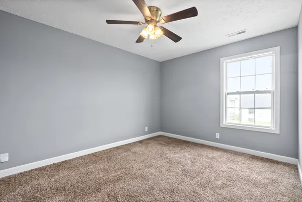 an empty room with windows and fan