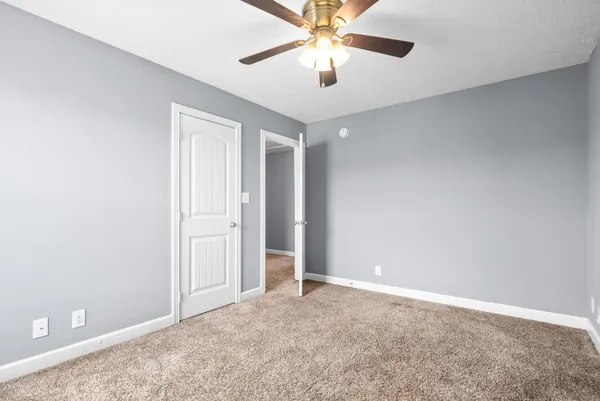 an empty room with closet and a chandelier fan