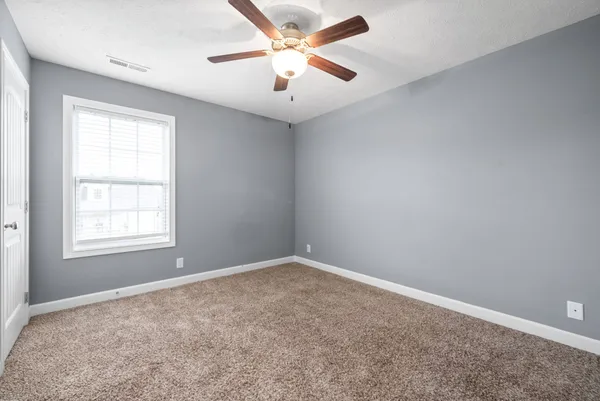 an empty room with a window and a fan
