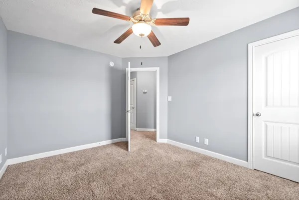 an empty room with closet and a chandelier fan