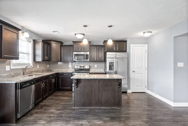 a large kitchen with stainless steel appliances kitchen island granite countertop a sink and cabinets