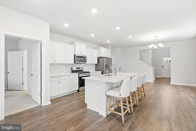 a kitchen with a dining table chairs wooden floor cabinets and entryway