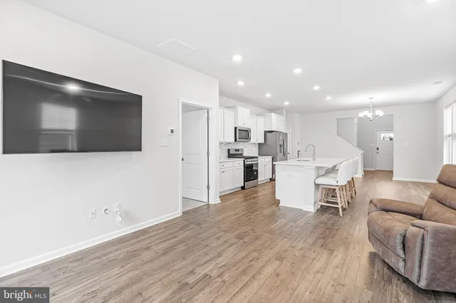 a living room with stainless steel appliances kitchen island furniture and a flat screen tv