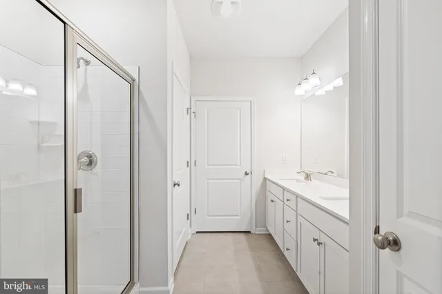 a spacious bathroom with a double vanity sink a mirror and a shower