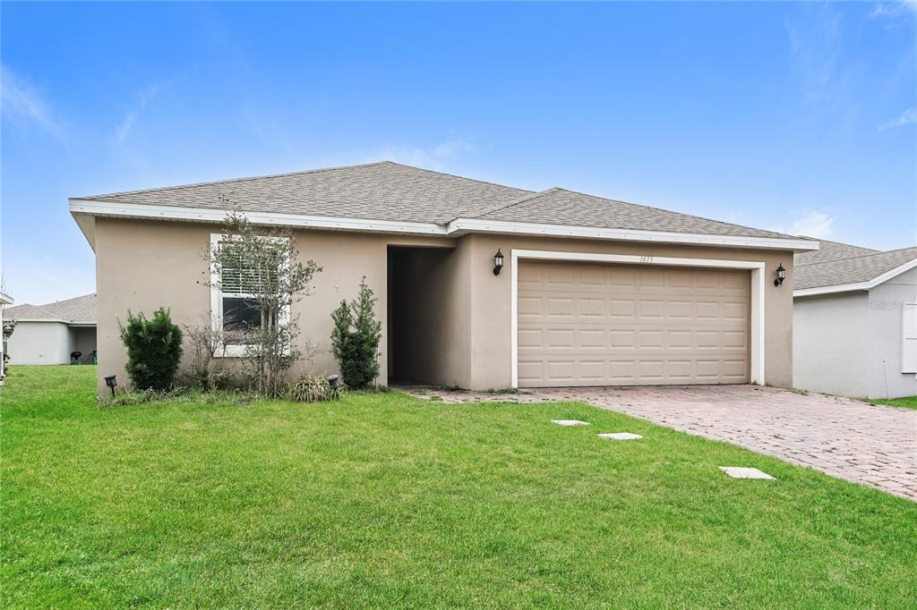 1473 Lucerne Loop Road Northeast Winter Haven, FL 33881 - Photo 2 of 25 a front view of house with yard and garage