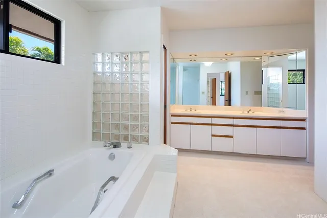 a bathroom with a tub a double vanity sink and a mirror