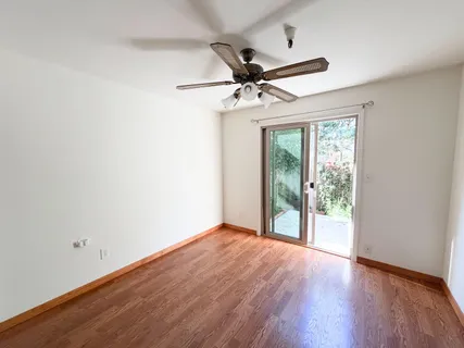 an empty room with wooden floor fan and windows