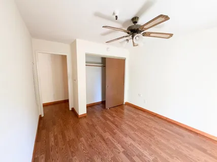 an empty room with wooden floor ceiling fan
