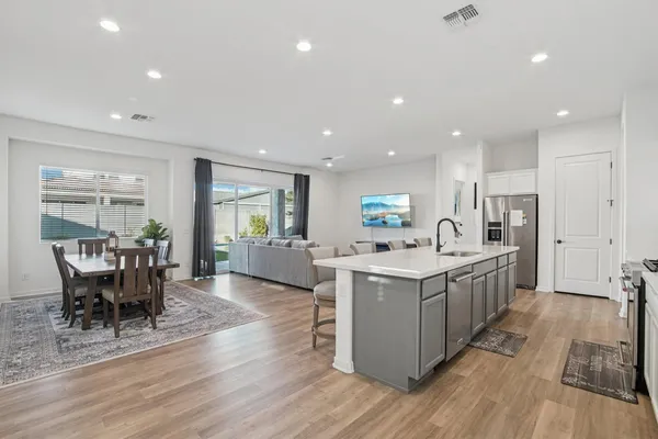a large kitchen with stainless steel appliances a large center island attached withe living room