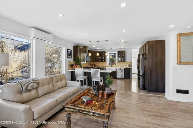 a living room with furniture and kitchen view with wooden floor