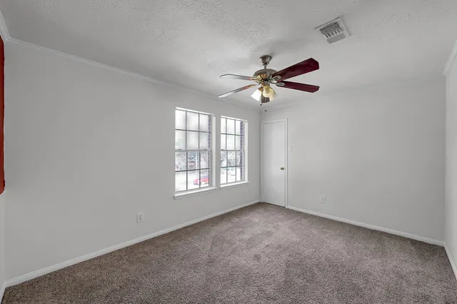 an empty room with chandelier fan and windows