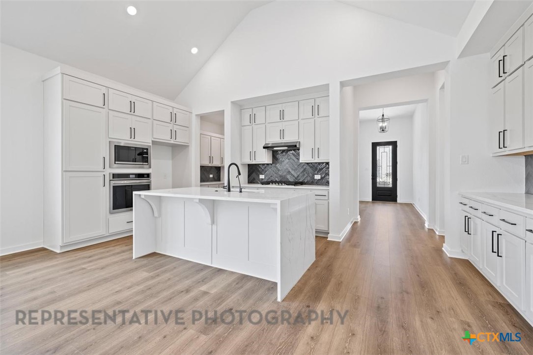 11925 Lofted Bloom Schertz, TX 78154 - Photo 3 of 12 a view of kitchen with stainless steel appliances granite countertop a stove top oven a refrigerator a sink and dishwasher with wooden floor