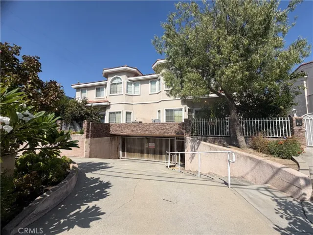 a view of a house with a small yard and large trees