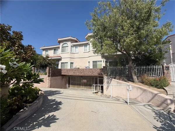 a view of a house with a small yard and large trees
