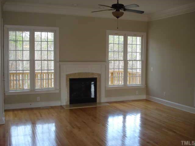 5308 Landguard Drive Raleigh, NC 27613 - Photo 5 of 12 an empty room with wooden floor a chandelier fan and windows
