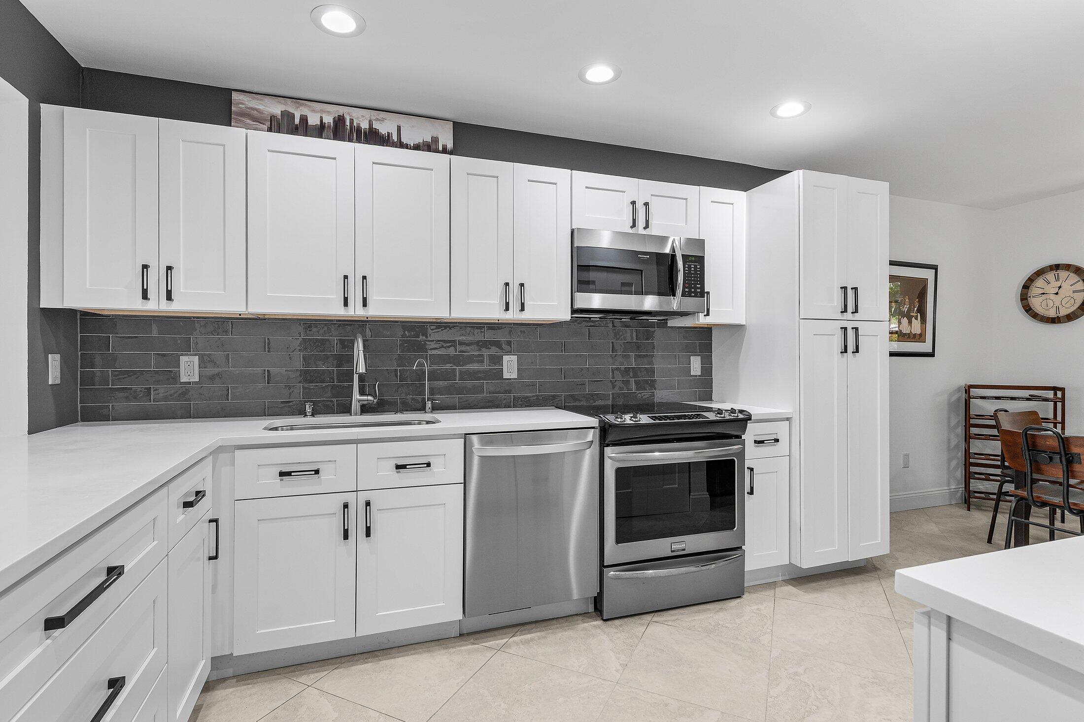 36 Westgate Lane, Unit D Boynton Beach, FL 33436 - Photo 11 of 51 a kitchen with stainless steel appliances granite countertop white cabinets a sink a stove a refrigerator and white cabinets