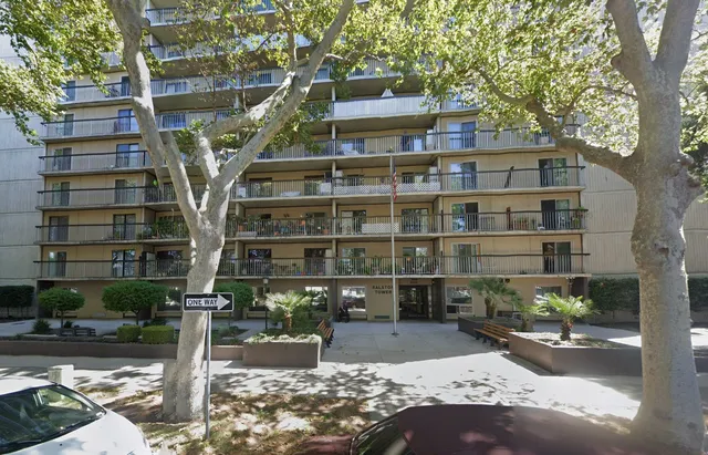 a view of a tall building with large tree