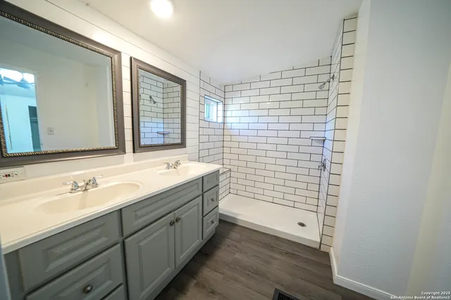 a bathroom with a double vanity sink a mirror and a shower