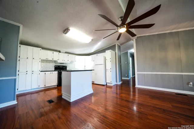 a view of a kitchen with a refrigerator a ceiling fan and wooden floor
