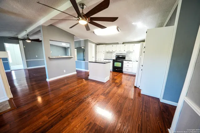 a view of a kitchen with wooden floor and a ceiling fan