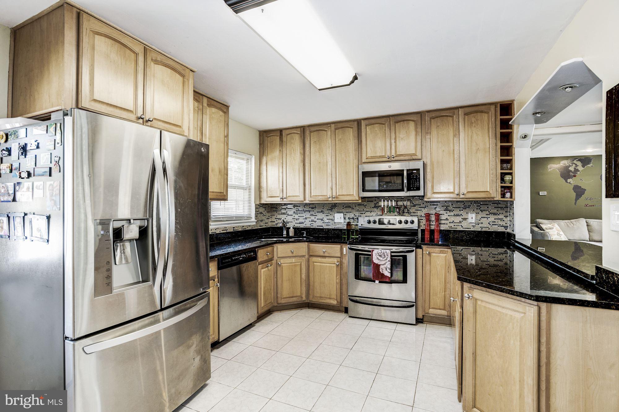 6708 Cimarron Street Springfield, VA 22150 - Photo 23 of 46 a kitchen with granite countertop a refrigerator stove and microwave