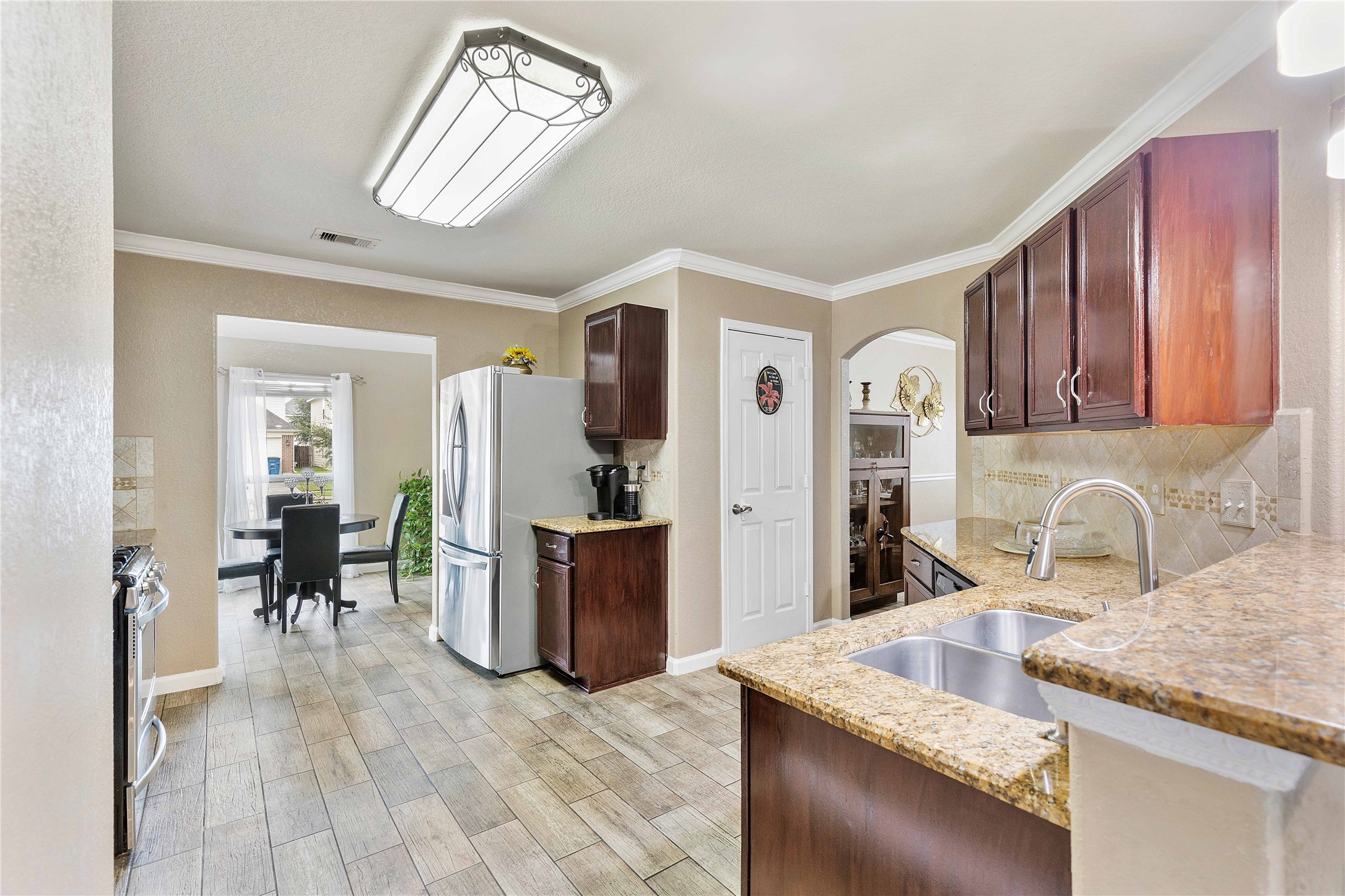 11031 Bauer Elm Street Houston, TX 77044 - Photo 11 of 33 This kitchen features sleek granite countertops, modern stainless steel appliances, and elegant wood cabinetry. It opens to a bright dining area with large windows, creating a seamless flow for easy entertaining.