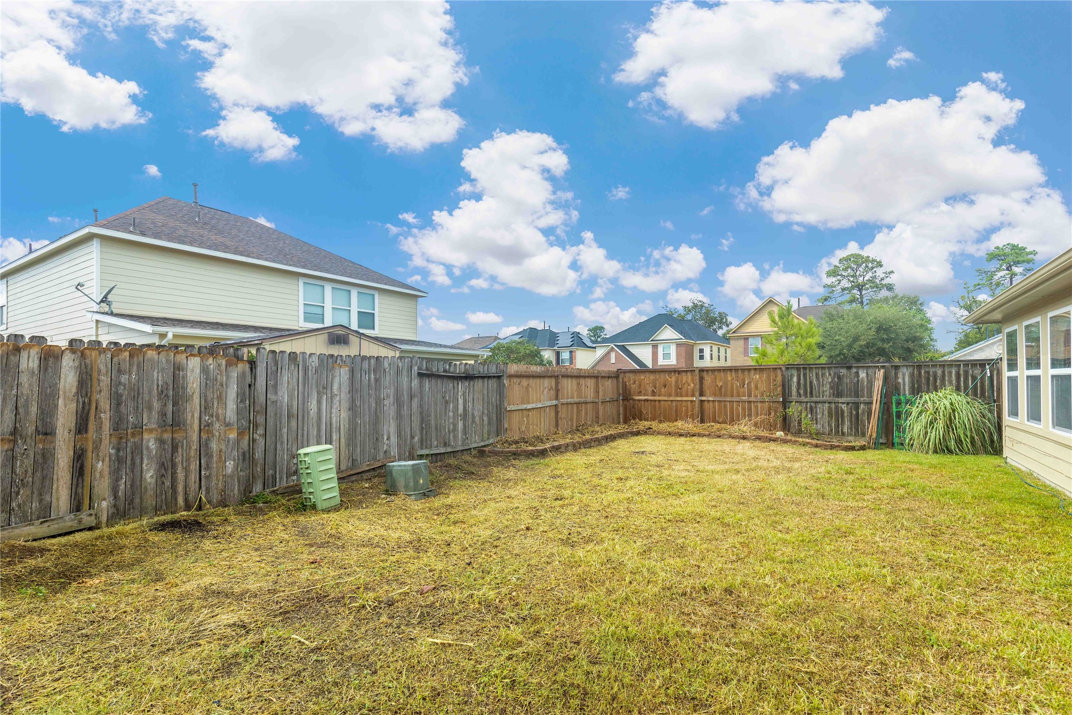 11031 Bauer Elm Street Houston, TX 77044 - Photo 31 of 33 This photo showcases a fenced backyard with a spacious grassy area, ideal for outdoor activities. The setting is bright and open, with neighboring houses visible, offering a suburban feel.