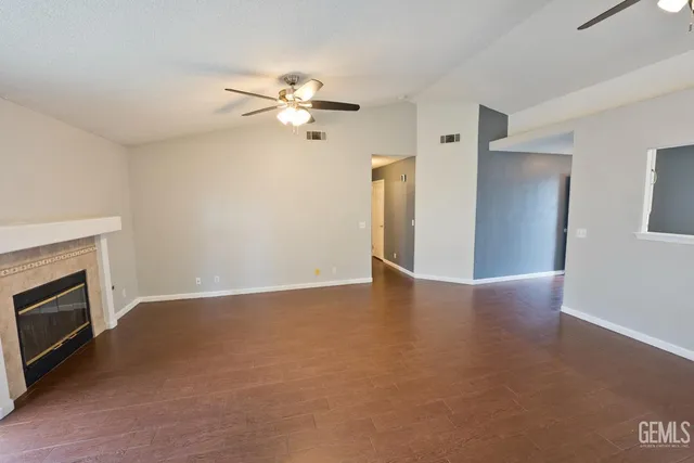 a view of an empty room with a ceiling fan and a fireplace