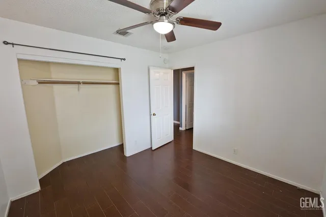 an empty room with wooden floor a ceiling fan and closet