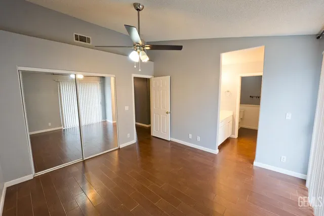 an empty room with wooden floor and a ceiling fan