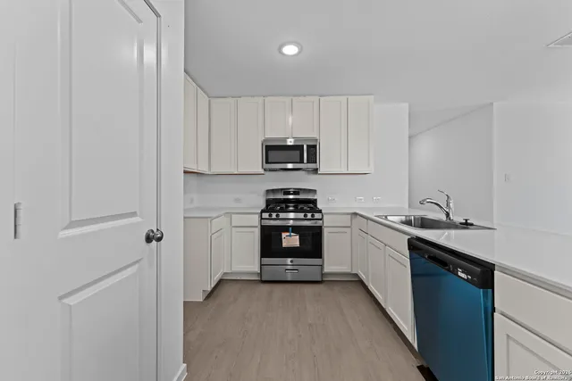 a kitchen with granite countertop a sink cabinets and stainless steel appliances