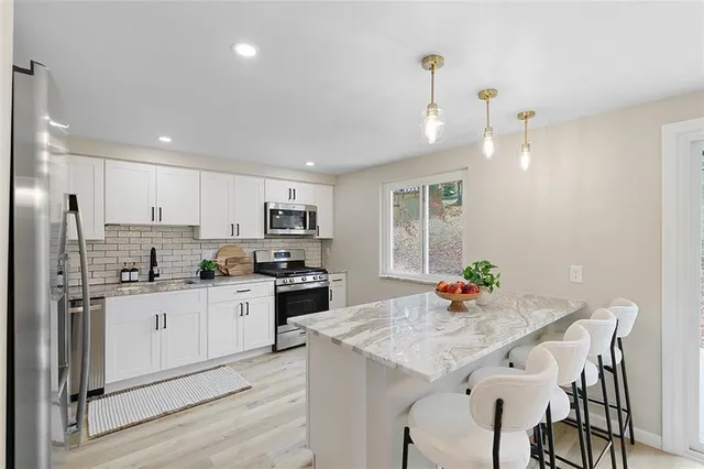 a kitchen with stainless steel appliances kitchen island granite countertop a refrigerator stove and oven