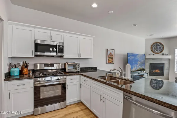a kitchen with granite countertop a sink stainless steel appliances and white cabinets