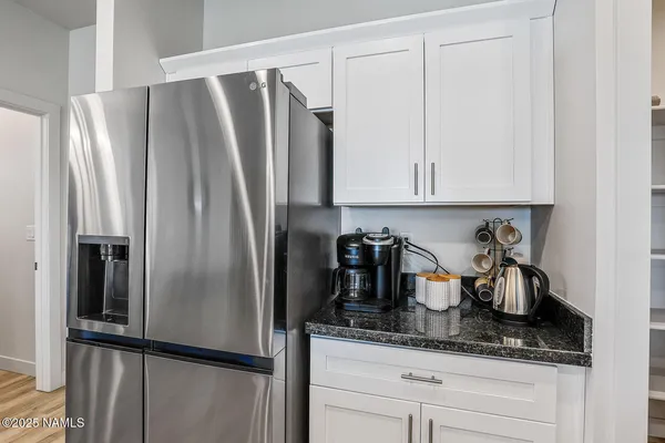 a kitchen with granite countertop a refrigerator and stainless steel appliances wooden floor