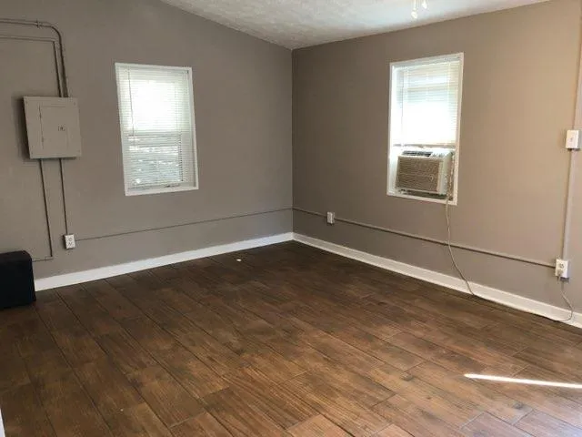 a view of an empty room with wooden floor and a window
