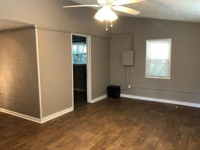an empty room with wooden floor and windows
