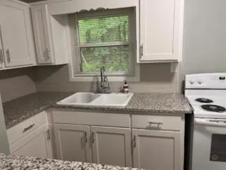 a kitchen with granite countertop white cabinets and a window
