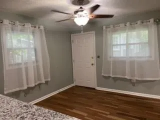 a view of a room with wooden floor and a ceiling fan