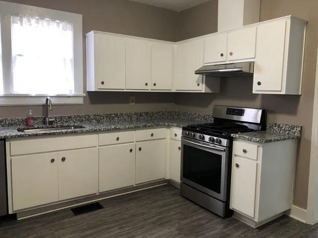 a kitchen with granite countertop white cabinets and a stove