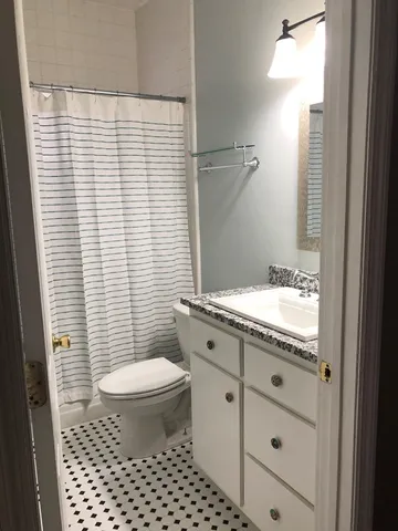 a bathroom with a granite countertop sink toilet mirror and a shower