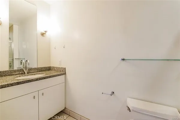 a bathroom with a granite countertop sink a toilet and a mirror