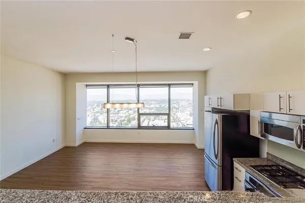 a view of a kitchen with refrigerator and wooden floor