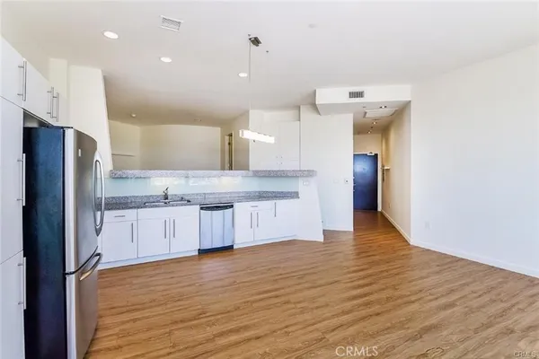 a large kitchen with a center island wooden floor stainless steel appliances and cabinets