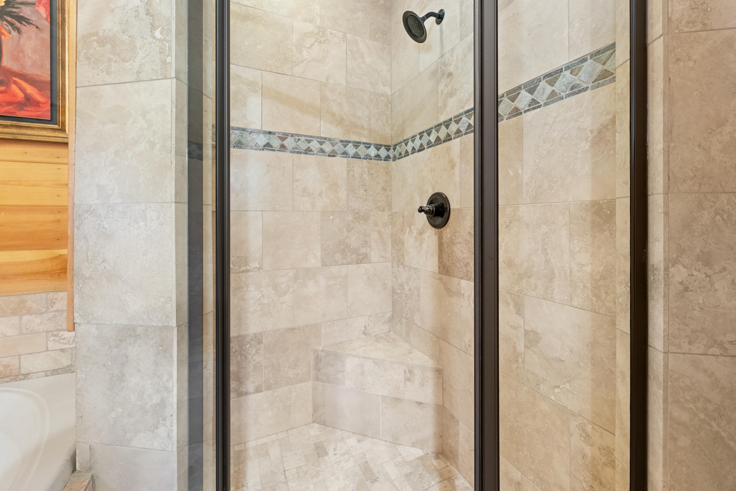 950 Cherry Road Eads, TN 38028 - Photo 13 of 30 Glass-enclosed shower featuring natural-tone tile, decorative accent tile band, built-in shower bench, and a dark bronze showerhead and control