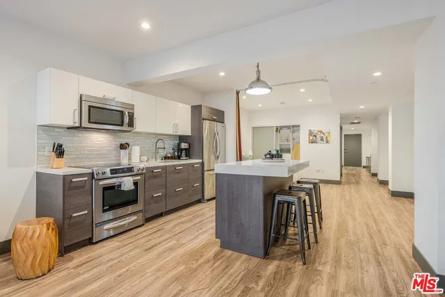 a kitchen with stainless steel appliances kitchen island granite countertop a stove a sink and a refrigerator