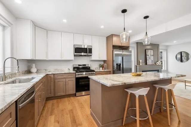 a kitchen with stainless steel appliances kitchen island granite countertop a sink stove and refrigerator